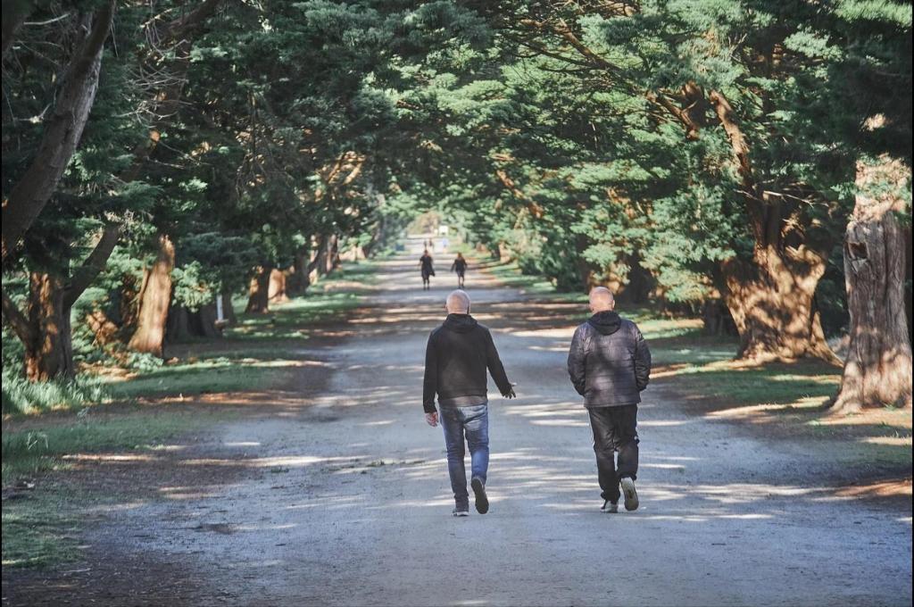 two men walking down a tree lined road at Classy Spaces Keysborough - New 2 Storey Townhouse in Keysborough