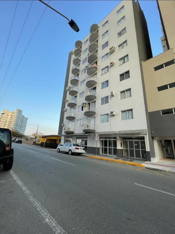 une voiture blanche garée devant un immeuble dans l'établissement Ap a 80m Praia Central de Barra Velha, à Barra Velha
