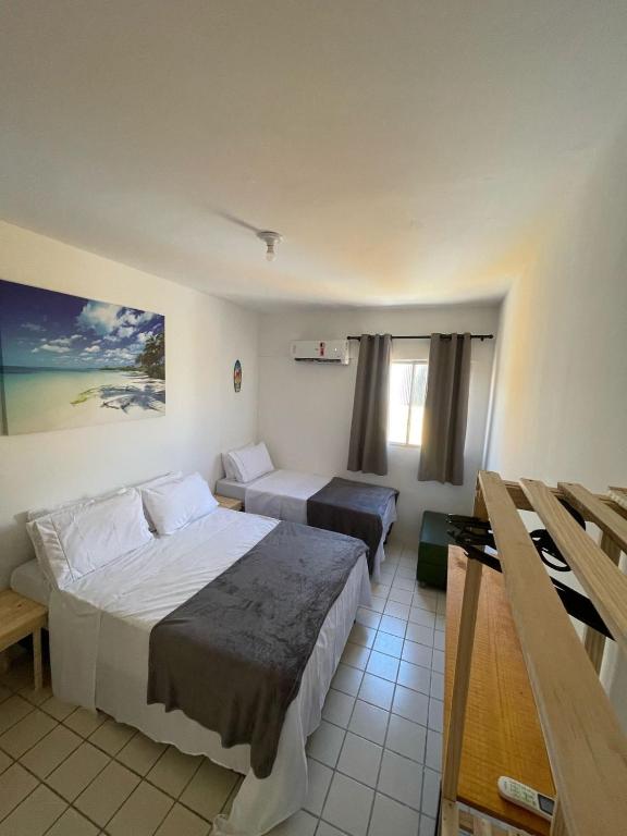 a hotel room with two beds and a window at Flat Barra Beach in Barra de São Miguel