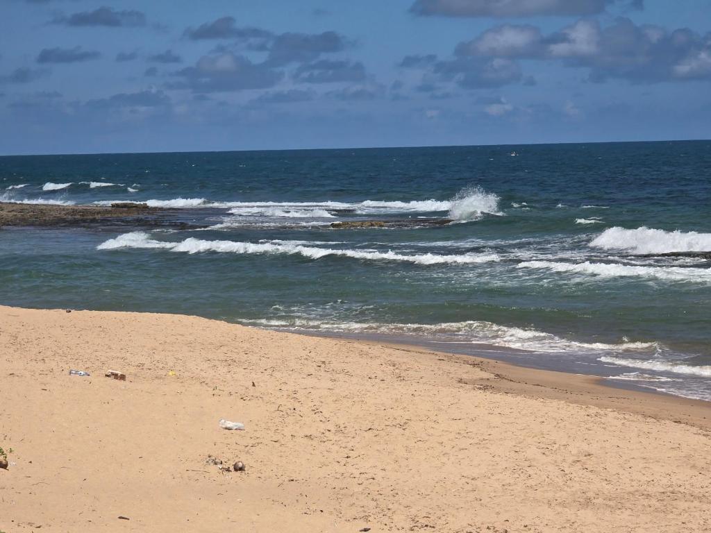 una playa de arena con olas en el océano en Pousada Doce Lar, en Camaçari