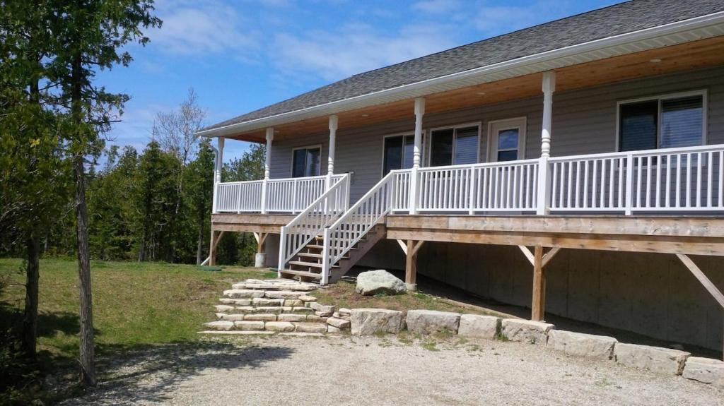 a house with a porch with a white deck and stairs at Family & Pet Friendly Huron Getaway in Miller Lake
