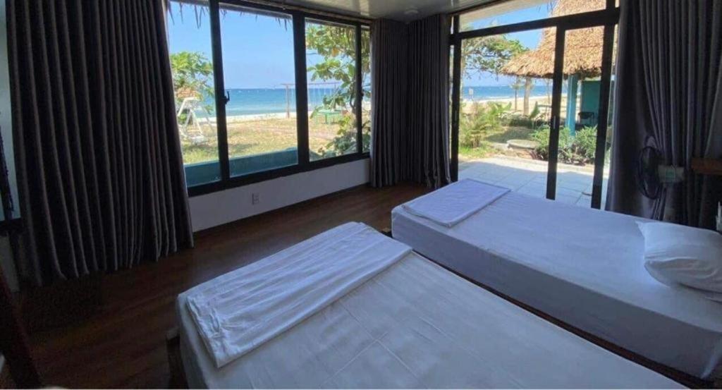 a bedroom with two beds and a view of the ocean at Seasand Quảng Bình - by BAY LUXURY in Dong Hoi