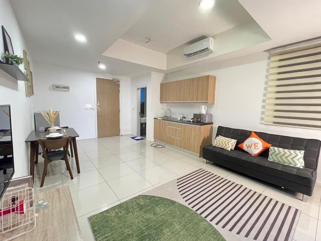 a living room with a black couch and a kitchen at The Cosmic - Icon City Petaling Jaya in Petaling Jaya