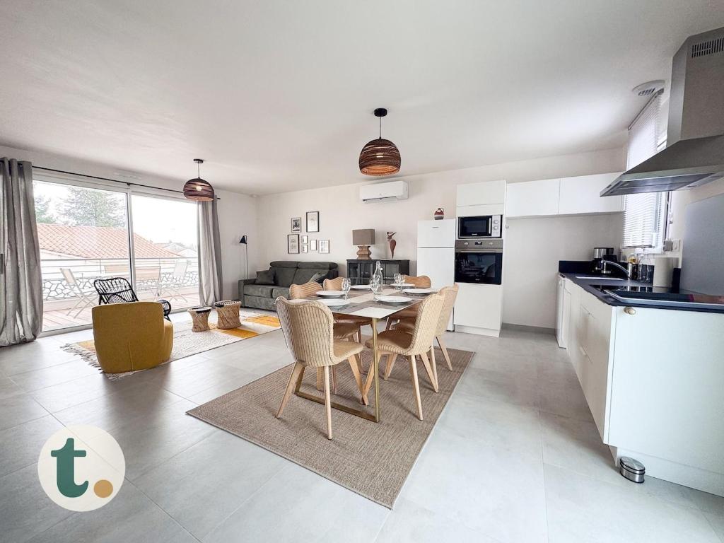 una cucina e un soggiorno con tavolo e sedie di Tranquiloue - Appartement neuf proche PuyduFou ! a Les Herbiers