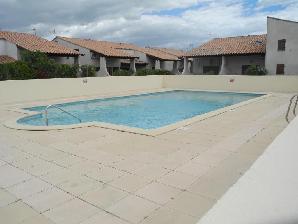 une grande piscine avec du carrelage et des maisons dans l'établissement Petite maison avec piscine et animaux admis - FR-1-475-146, à Saintes-Maries-de-la-Mer
