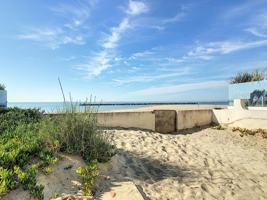une plage de sable avec l'océan en arrière-plan dans l'établissement Appartement T4 en bord de plage avec terrasse et parking à Carnon - FR-1-715-103, à Mauguio