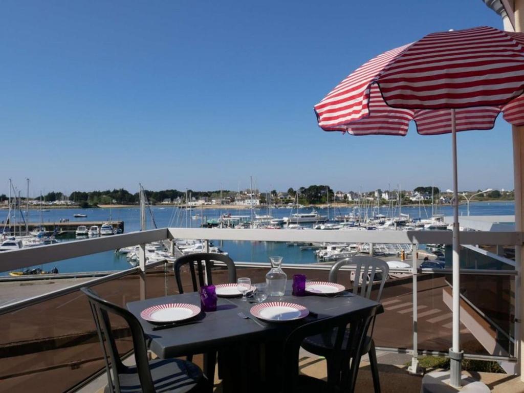 - une table avec un parasol sur un balcon avec un port de plaisance dans l'établissement Étel : Appt Duplex 3 Pièces 45m² - Piscine - Animaux Bienvenus - FR-1-479-216, à Étel