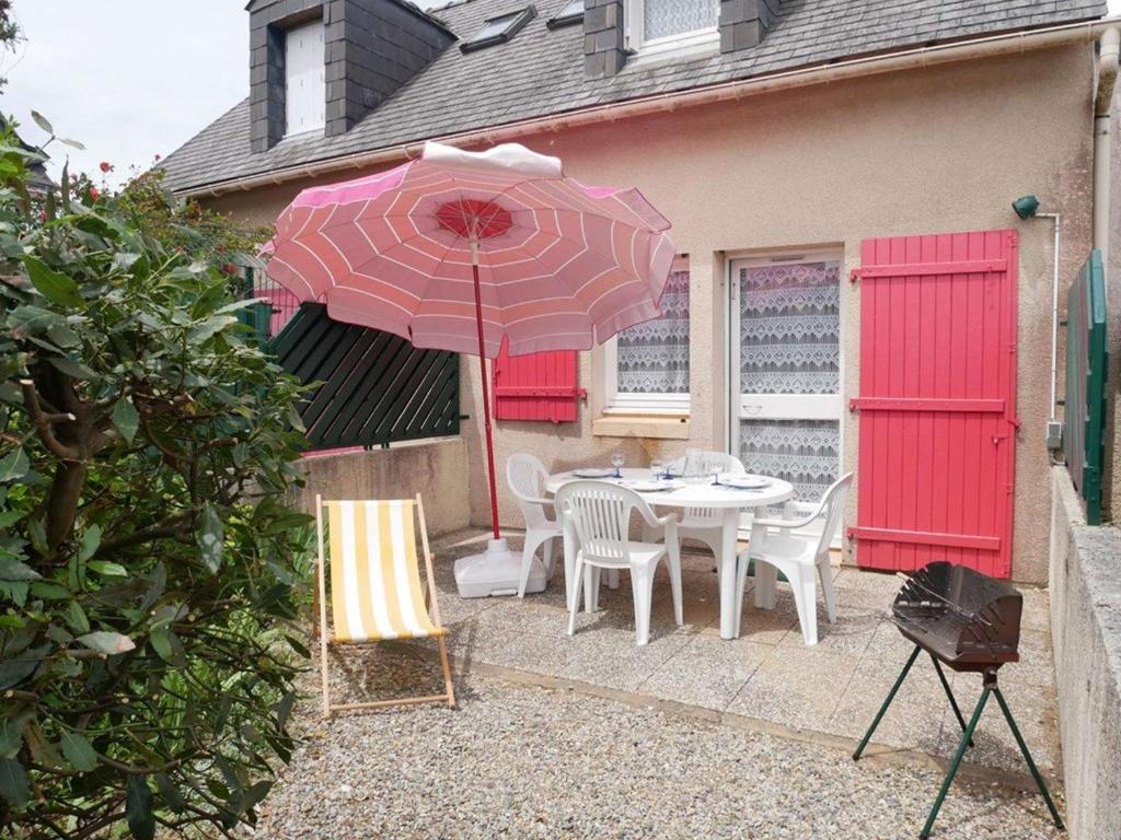 une terrasse avec une table et un parasol rose dans l'établissement Maisonnette Erdeven 3 pièces, proche plage, parking - FR-1-479-219, à Erdeven