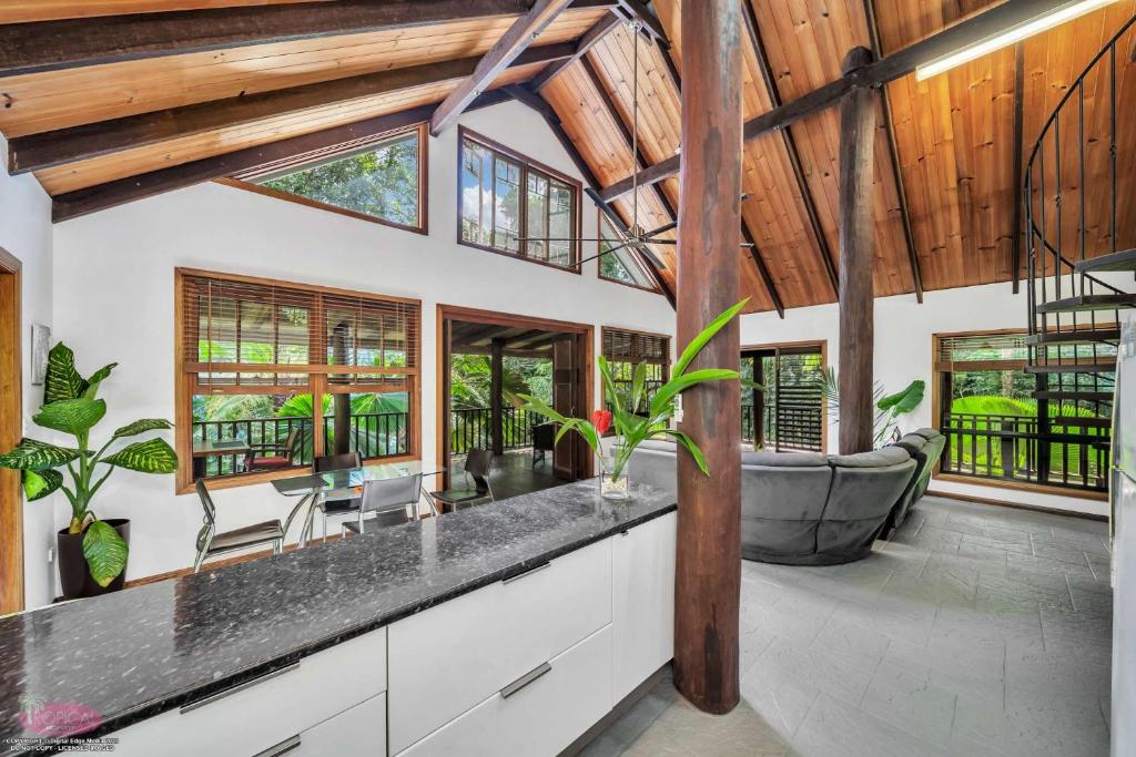 cocina abierta con techos de madera y sala de estar. en Fern House, en Kurrimine Beach