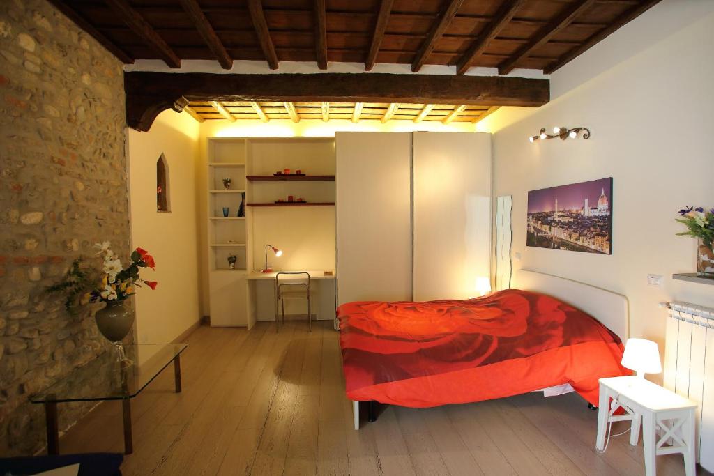 フィレンツェにあるVisit Florentia Apartmentの赤いベッドと石の壁が備わるベッドルーム1室