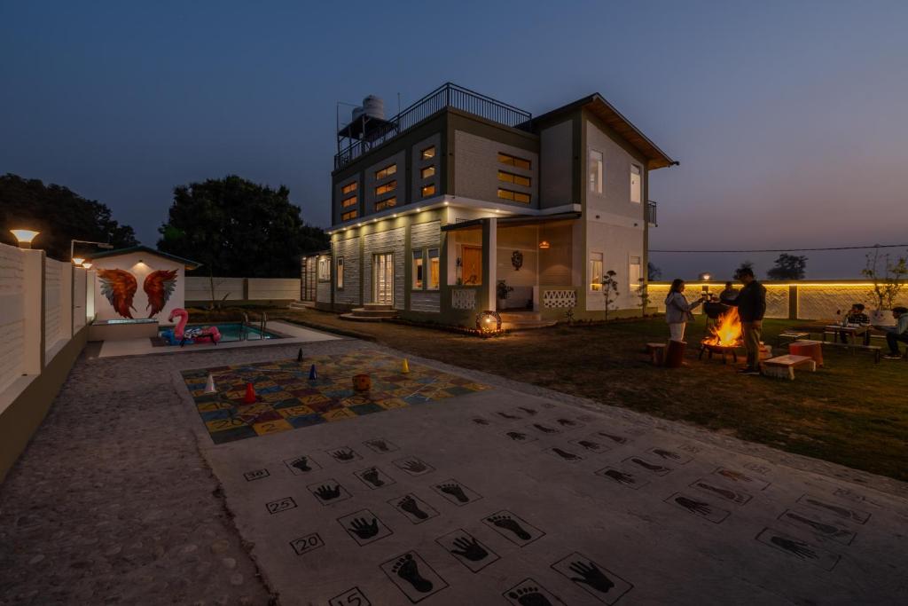 a house with people standing outside of it at SaffronStays Sher Bagh - 4BR eco-friendly pool villa with jungle trails, farm-to-table meals & bonfire nights near Corbett Park in Belparāo