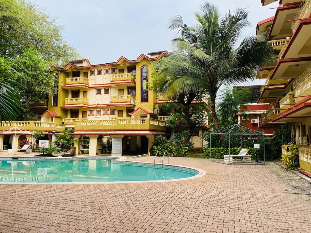 a hotel with a swimming pool in front of a building at Candolim Beach Apartments Goa in Candolim