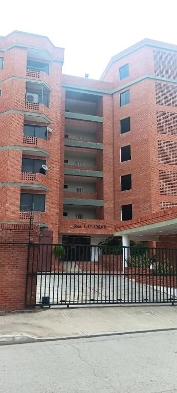 a brick building with a fence in front of it at residencias lalamar in Chichiriviche