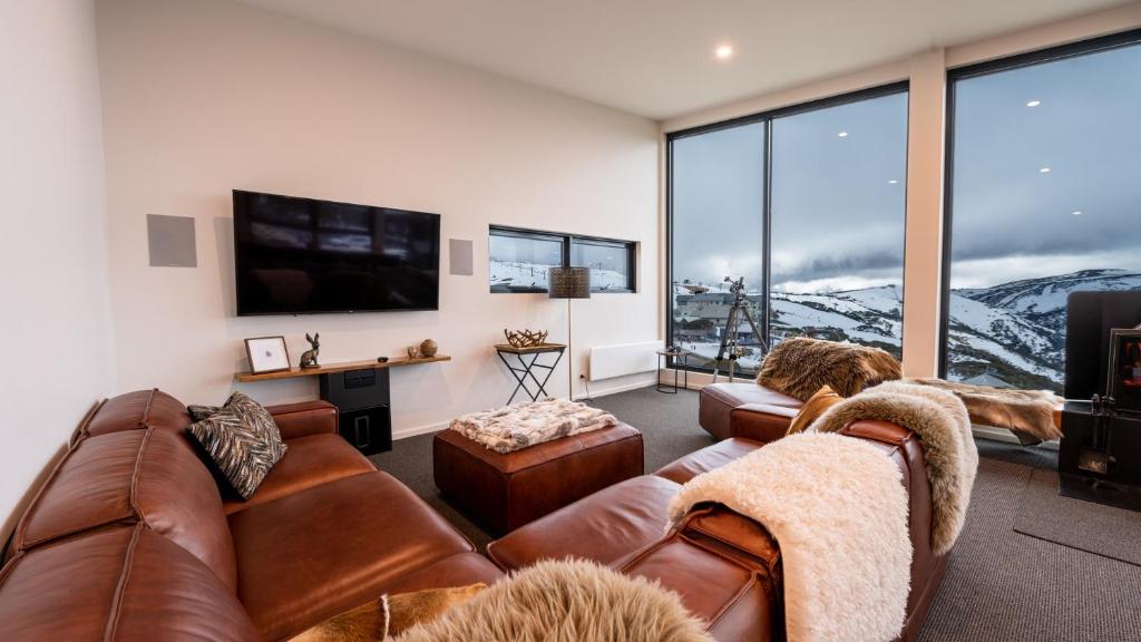 a living room with two brown leather couches and a flat screen tv at Whitemount in Mount Hotham