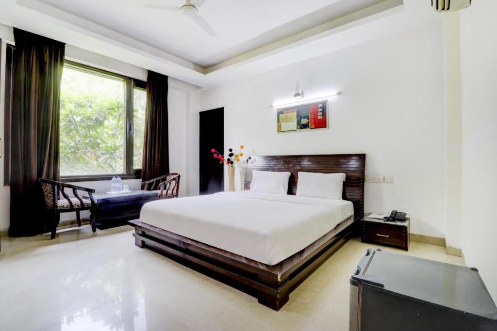 a bedroom with a bed and a desk and a window at Blue Moon Residency Hotel & Restaurant in Gurgaon