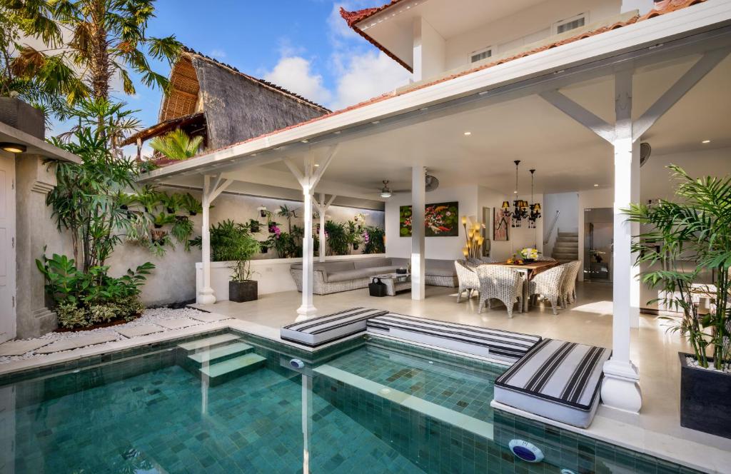 an outdoor living area with a swimming pool and a house at Ozamiz Villa Seminyak by Bali Villas R Us in Seminyak