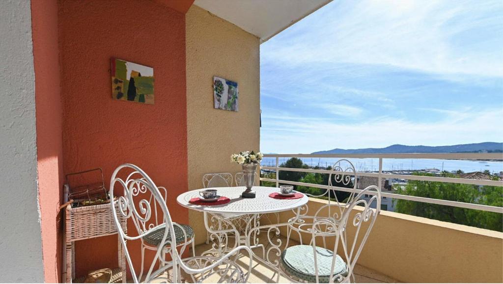 d'un balcon avec une table et des chaises et une vue sur l'eau. dans l'établissement Le Marbello- Vue mer- Plages- Commerces, au Lavandou