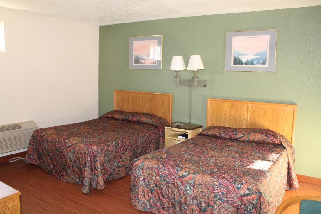 una camera d'albergo con due letti e pareti verdi di American Motor Inn - Rock Island a Rock Island