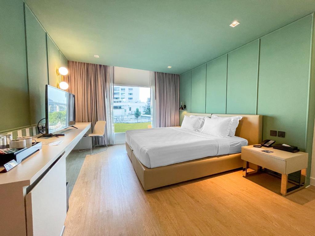 een slaapkamer met een bed en een bureau met een televisie bij Happihaus Hotel Bangkok in Bangkok