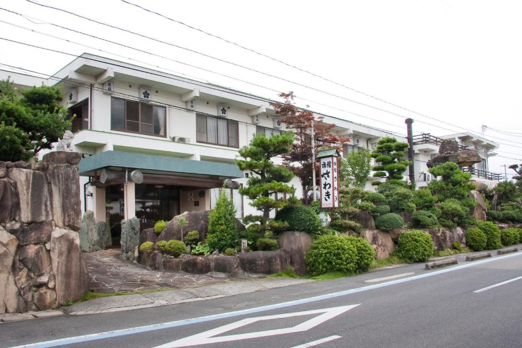 un bâtiment situé sur le côté d'une rue bordée d'arbres et de buissons dans l'établissement Sawaki, à Imabari