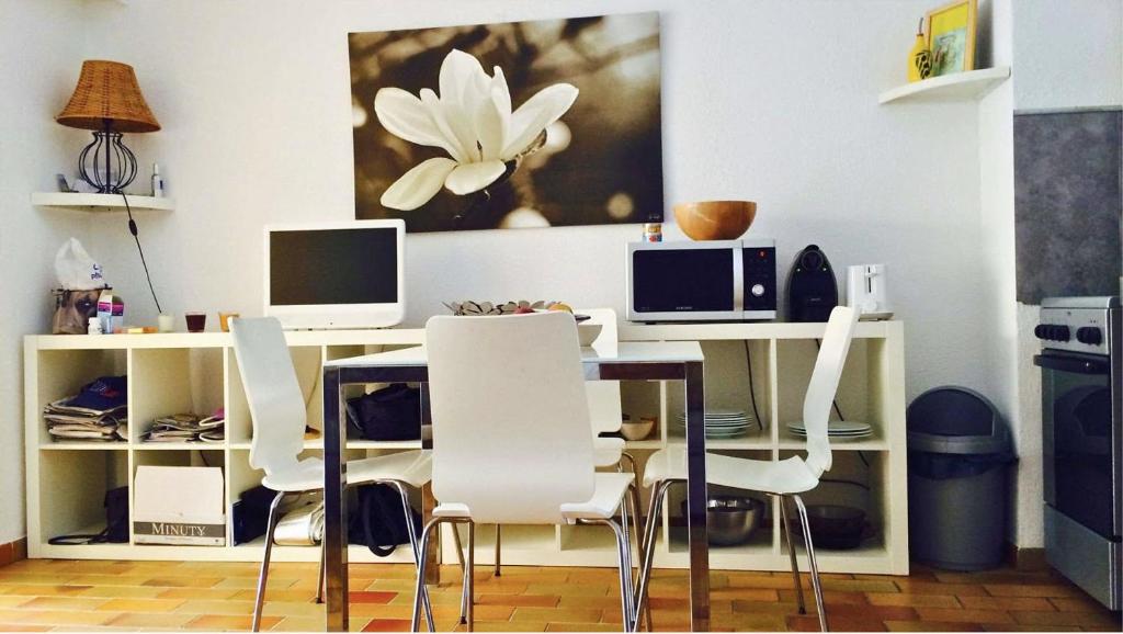 Cette chambre comprend un bureau avec deux moniteurs et des chaises blanches. dans l'établissement T2 en rez de jardin , proche plage de St Clair et commerces, au Lavandou