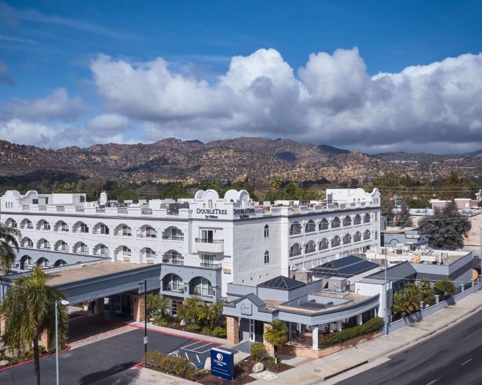 查茨沃斯DoubleTree by Hilton Chatsworth的一座白色的大建筑,背景是群山