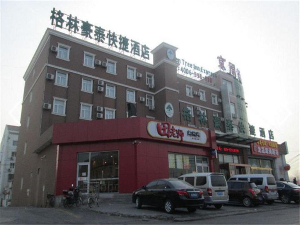 um grande edifício com carros estacionados em frente em GreenTree Inn Beijing Fangshan Liangxiang Suzhuang Express Hotel em Fangshan