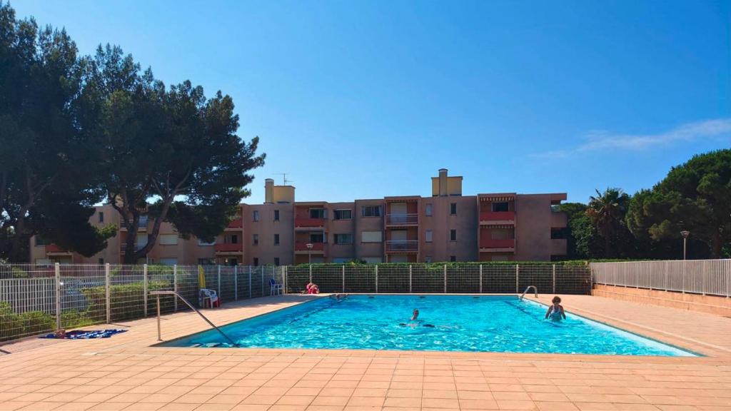 - une piscine avec des personnes devant un bâtiment dans l'établissement T2- Parking- Plages- Commerces, à Bormes-les-Mimosas