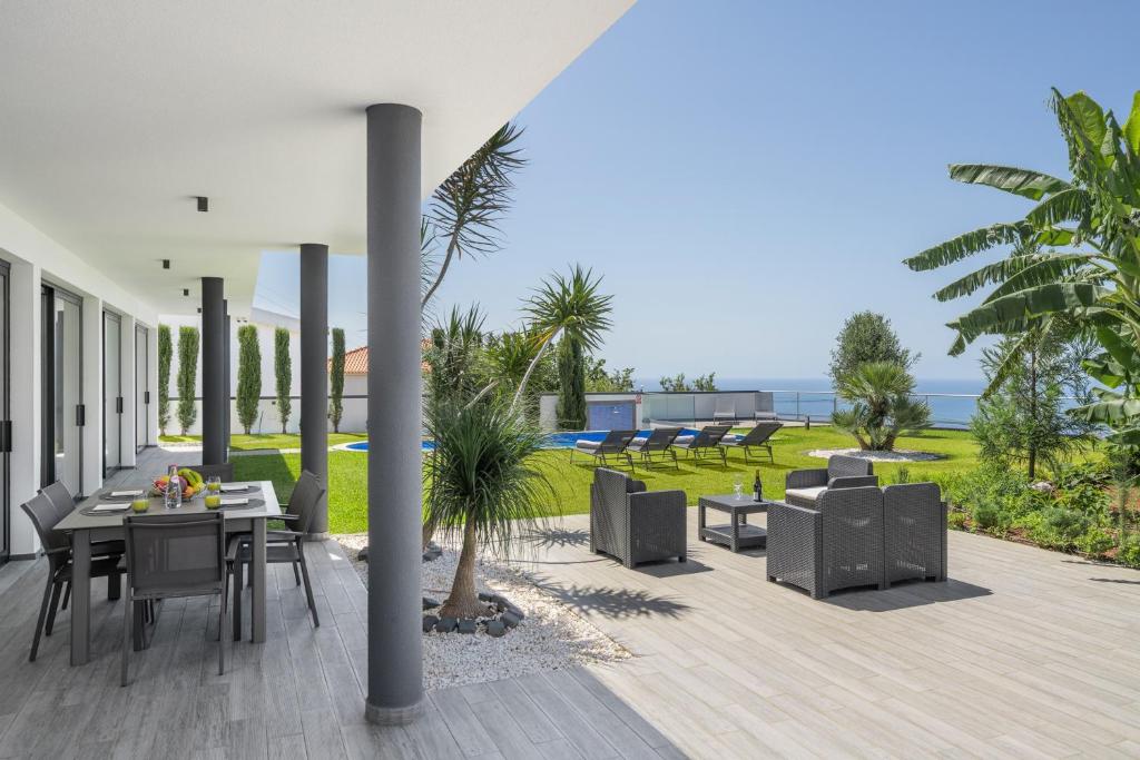a patio with a table and chairs and the ocean at Modern villa pool garden seaview Ocean Sunset in Caniço