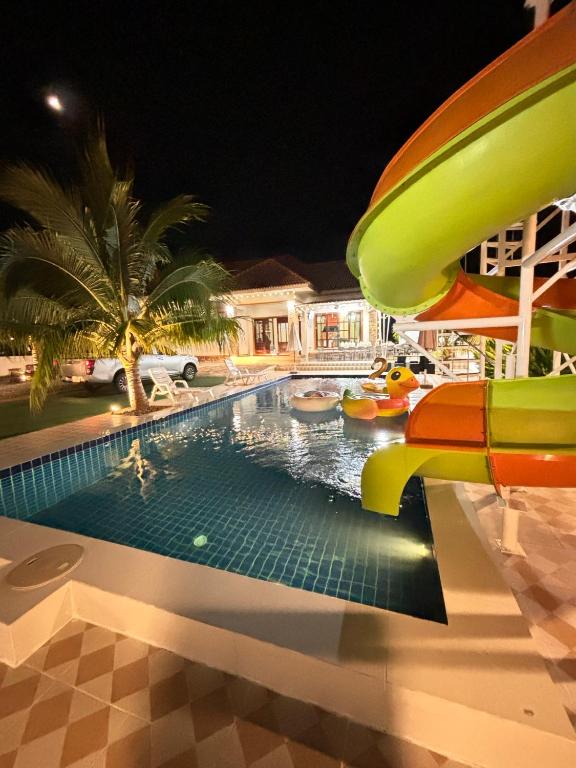 a swimming pool at night with a pool slide at ชิลชิลขนอมพูลวิลลา in Ban Thong Ching