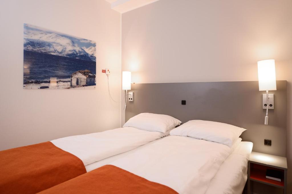 a bedroom with two beds and a painting on the wall at Pingvinhotellet UNN Tromsø in Tromsø