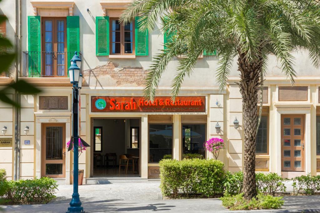 a building with a palm tree in front of it at Sarah Hotel Halal Restaurant Phu Quoc in Phu Quoc