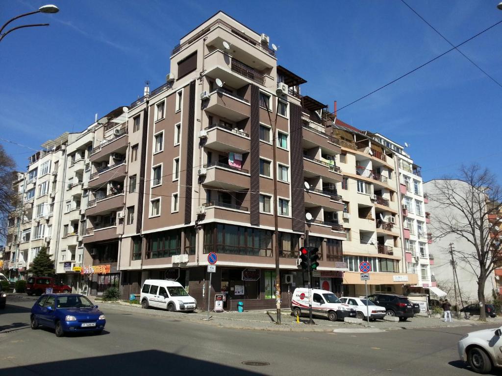 un edificio alto con coches estacionados frente a él en Apartment Nova, en Burgas