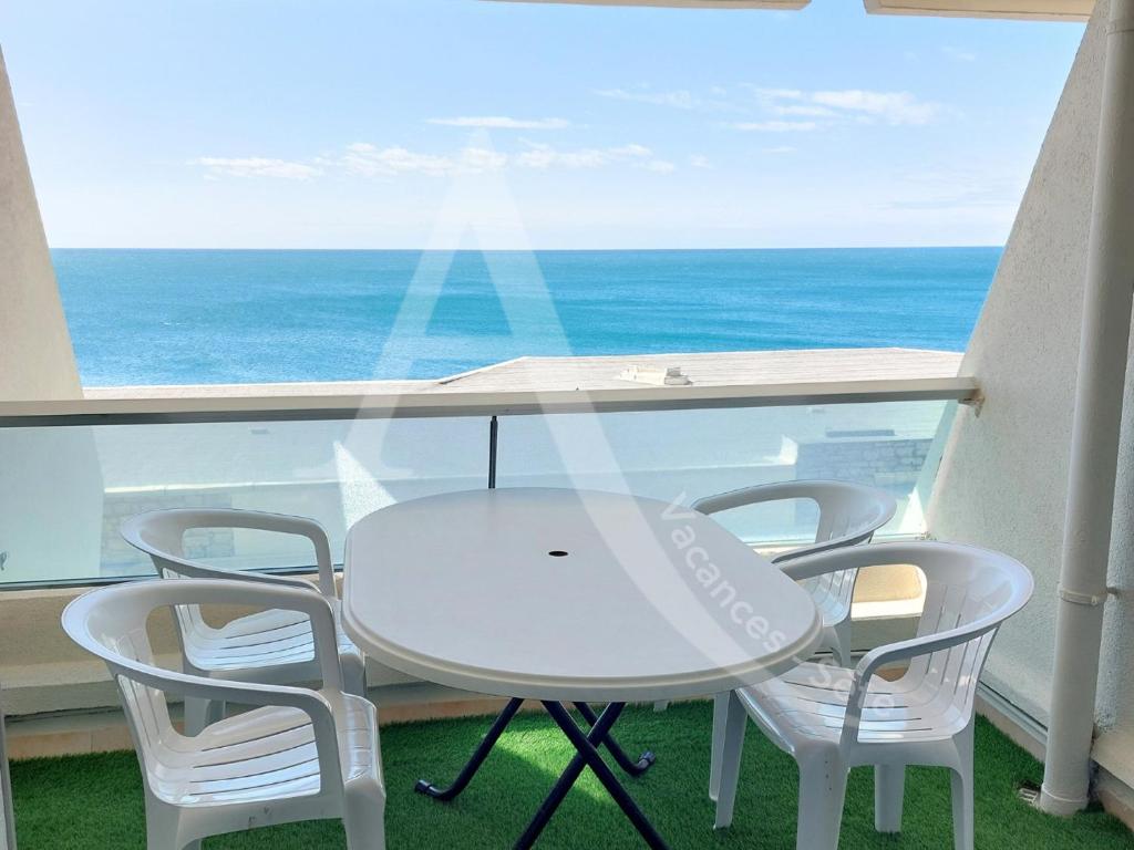 une table blanche et des chaises sur un balcon avec l'océan dans l'établissement T2 4 personnes avec balcon vue mer tout equipe, à Sète