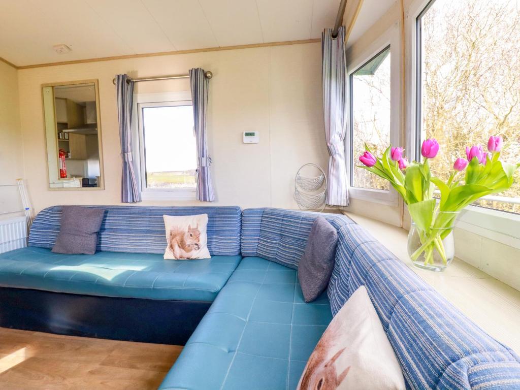 a blue couch in a living room with flowers at Little Trevorrick Caravan in Wadebridge