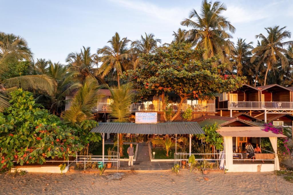 a resort on the beach with palm trees in the background at Sea Star Resort in Agonda