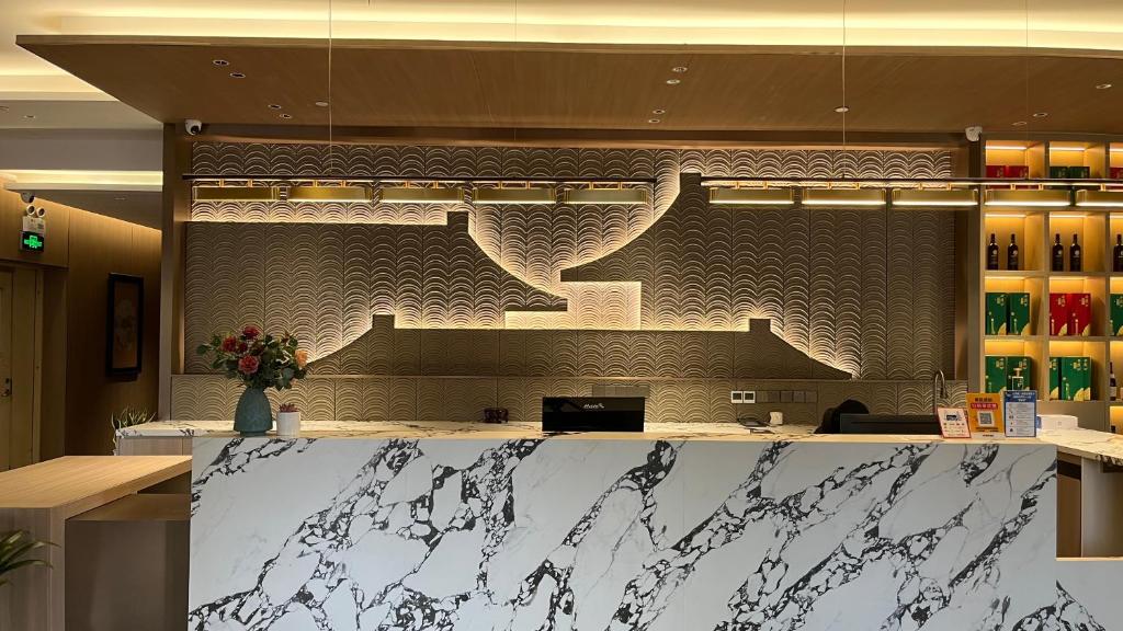 a lobby with a counter with a staircase on the wall at 西安隐逸雅致酒店The Elegant Hotel- 南二环店South 2ndRing Road in Xi'an