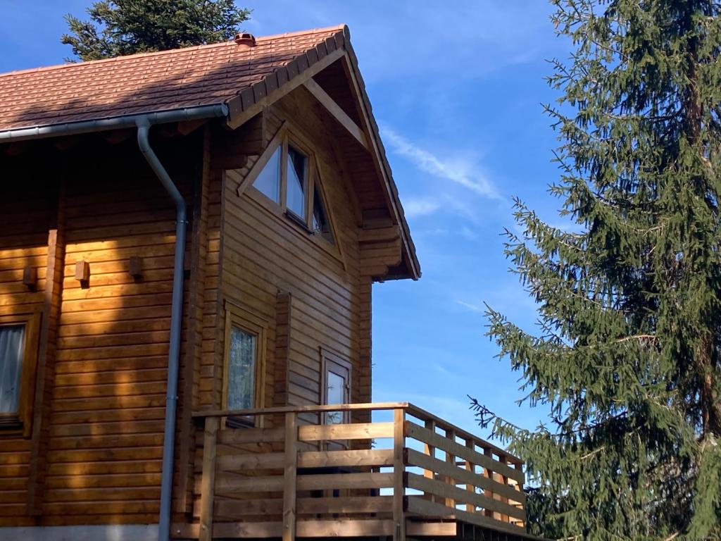 a log cabin with a deck and a tree at Chalet Mon Beau Sapin lisière de Forêt - Vue montagne - Gerardmer in Anould