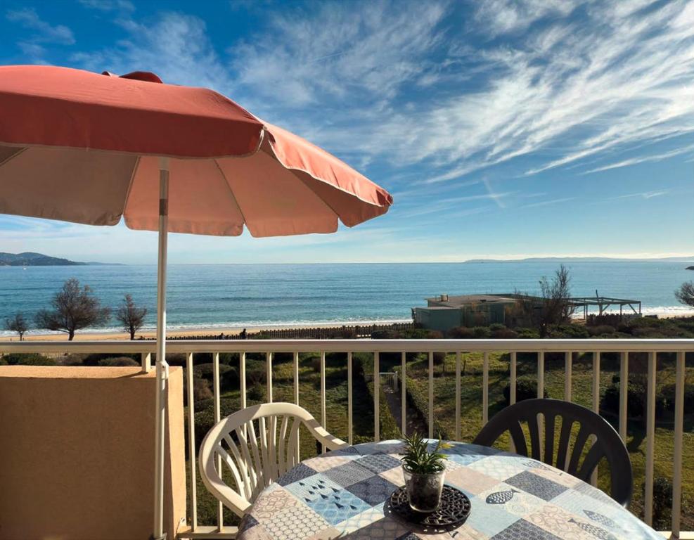 - une table avec un parasol sur un balcon donnant sur l'océan dans l'établissement T2 pied dans l'eau- Vue mer- Proche commerces, au Lavandou