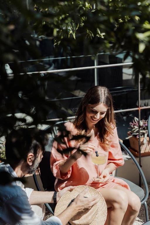 a woman sitting on a chair holding a drink at Domìa Boutique Hotel e Cucina in Mondello