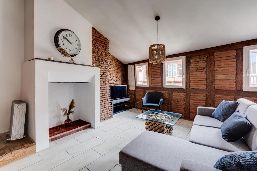 un salon avec un canapé et une horloge au mur dans l'établissement L'Authentique des Carmes, à Toulouse