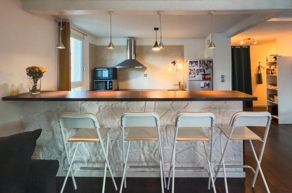 une cuisine avec un bar avec quatre tabourets dans l'établissement T3 spacieux - climatisé - commerces - plages, au Lavandou