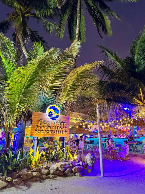 a sign on a beach with palm trees at night at Casa Pilar Beach Resort in Boracay