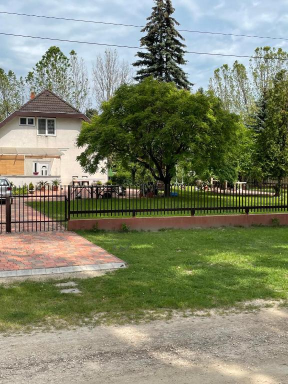 a fence in front of a house with a tree at Gold Apartman in Zamárdi