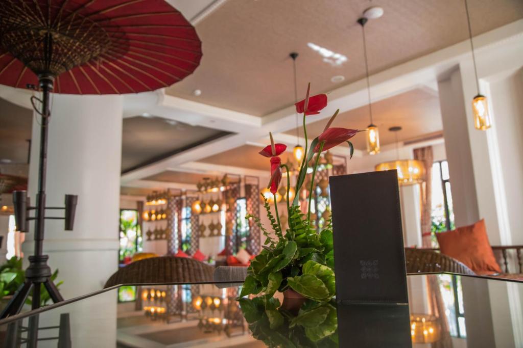 a vase with red flowers on a table in a store at Rose Garden Hotel in Yangon