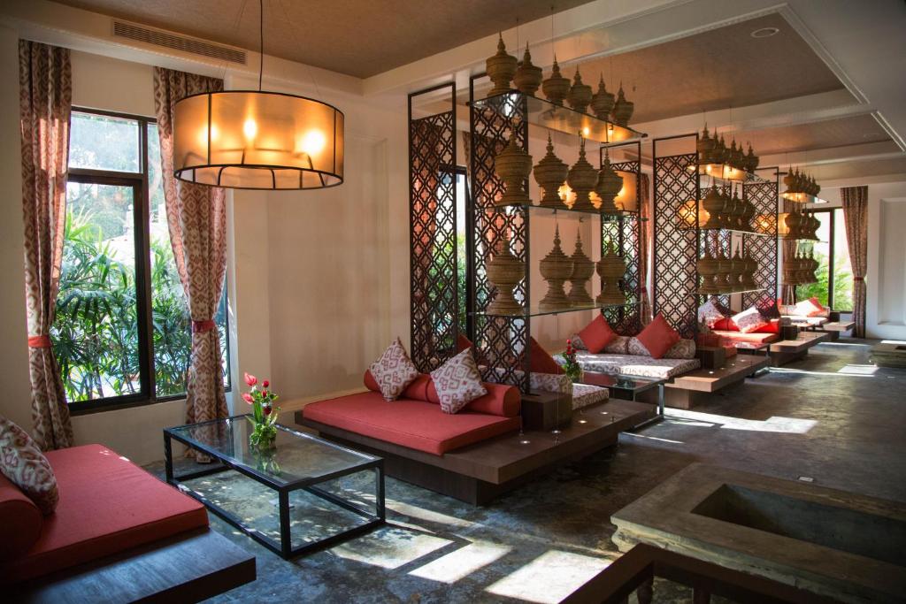 a living room with red couches and a large mirror at Rose Garden Hotel in Yangon