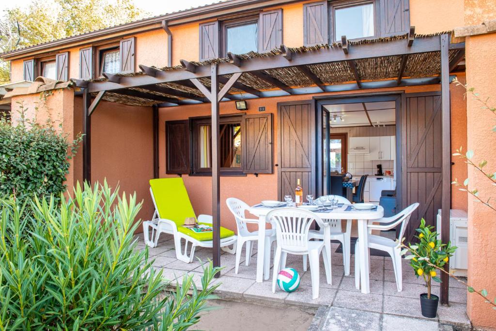 Un patio con una mesa y sillas en un patio. en Les Tamaris et Les Portes du Soleil, en Portiragnes