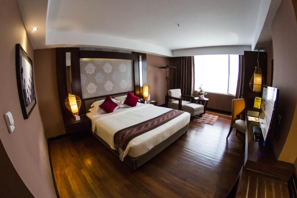 a bedroom with a large bed and a living room at Rose Garden Hotel in Yangon