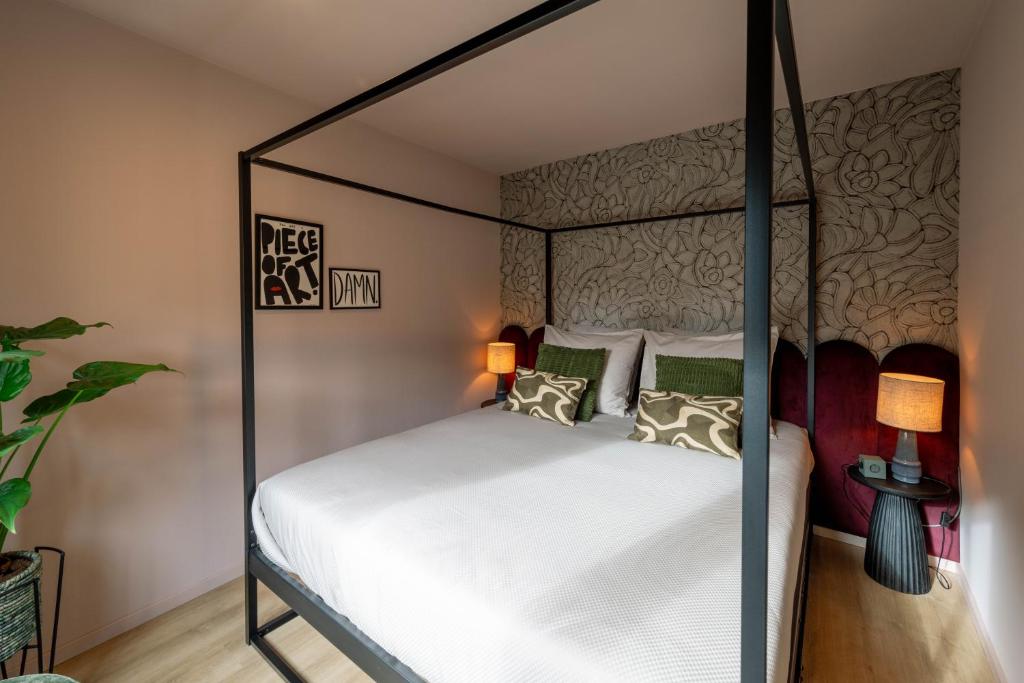 een slaapkamer met een hemelbed met witte lakens en kussens bij Little Jack Boutique Studios in Valkenburg