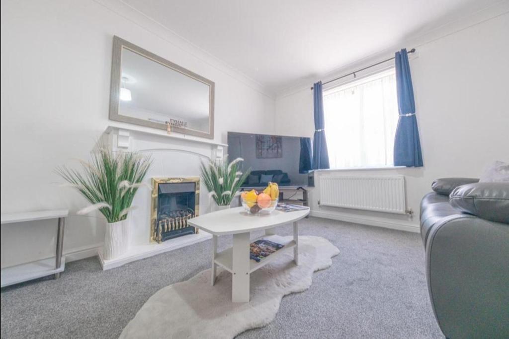 a living room with a couch and a fire place at Sleeps 5 - Private Garden- Free Parking in Corby